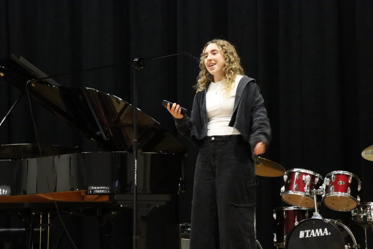Senior Celina Mouchi smiles at the audience while singing along to a Stevie Wonder song