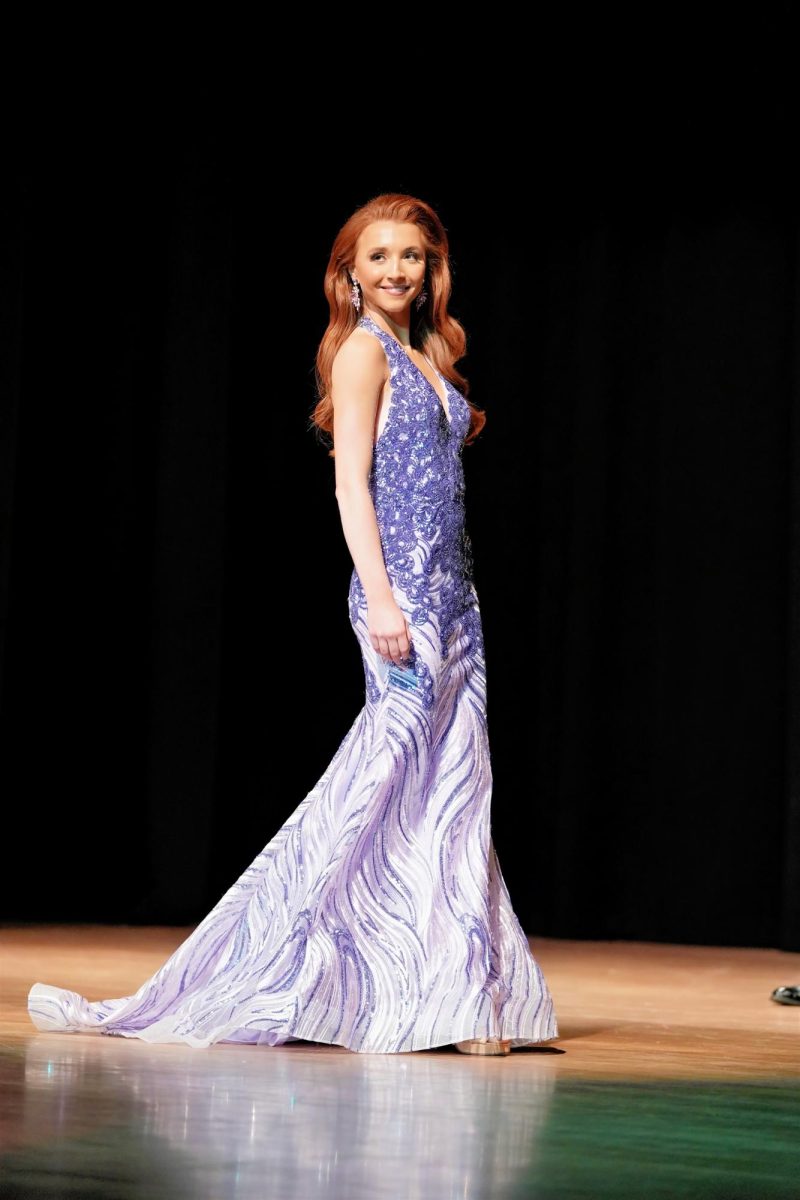 Modeling a purple halter-style beaded gown, Everly Wade walks the stage during formalwear. 